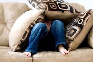Little boy hiding behind cushions