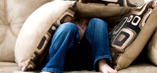 Little boy hiding behind cushions